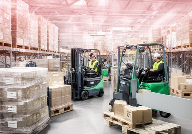 Sector logístico con carretillas, pallets preparados y personal coordinando salidas de pedidos en planta